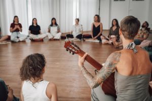 Menschen sitzen im Kreis, eine Person spielt Gitarre